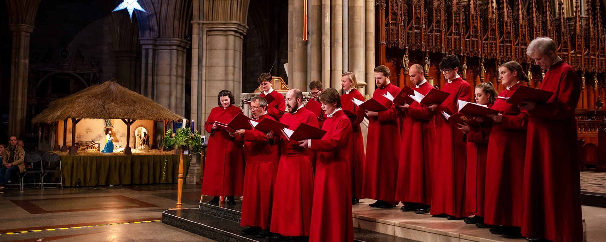 Truro Cathedral Choir singing beside a large crib