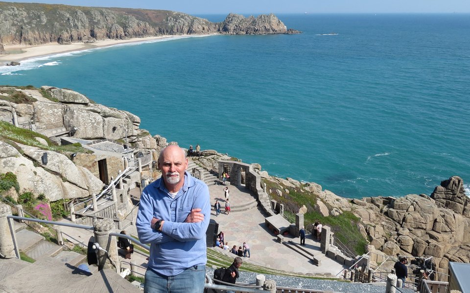 Phil Jackson, tour leader, with the Minack and bay in the background
